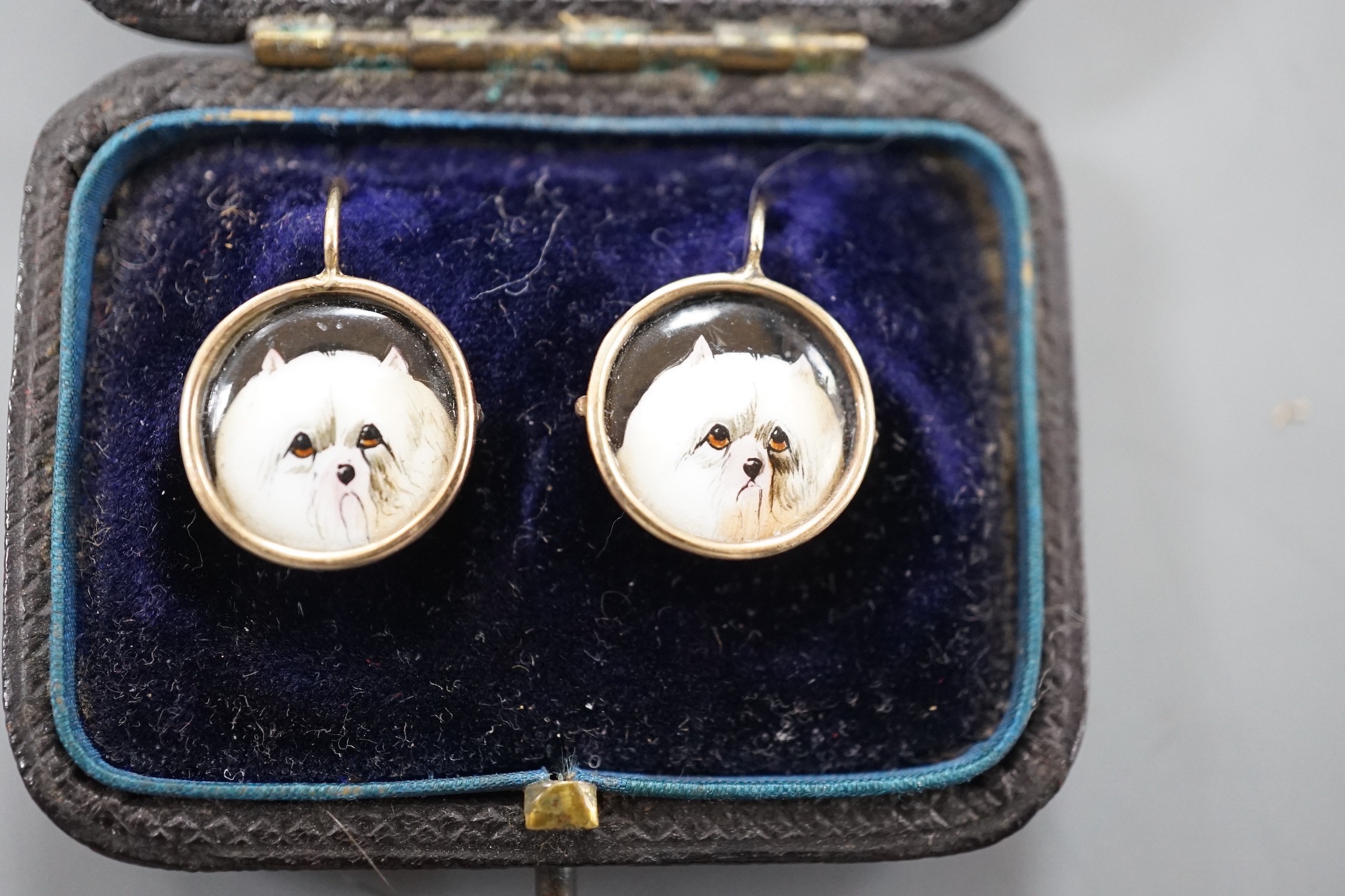 A cased pair of yellow metal and circular enamel earrings, decorated with the heads of a dog, diameter 14mm, gross weight 2.8 grams.